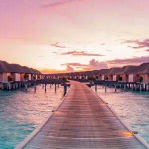 stunning sunset over beach huts at a luxury resort in the maldives