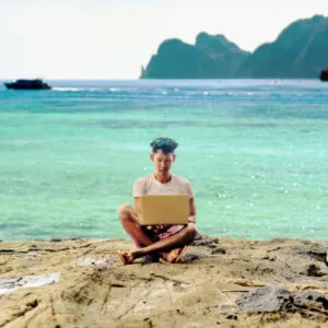 man working by the tropical sea with his laptop