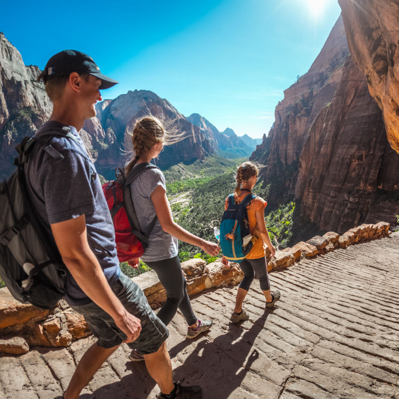 three hikers walking down a path with amazing canyon views in the ...