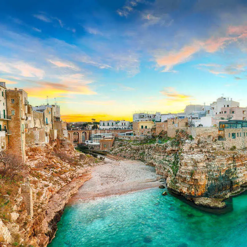 Americans Can Fly Nonstop To This Italian City With Cheaper Prices & Smaller Crowds Panoramic View Of Cala Paura Gulf In Polignano a Mare, Puglia, Italy, Southern Europe