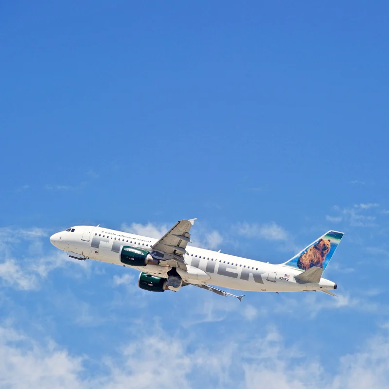 Frontier plane flying in blue sky