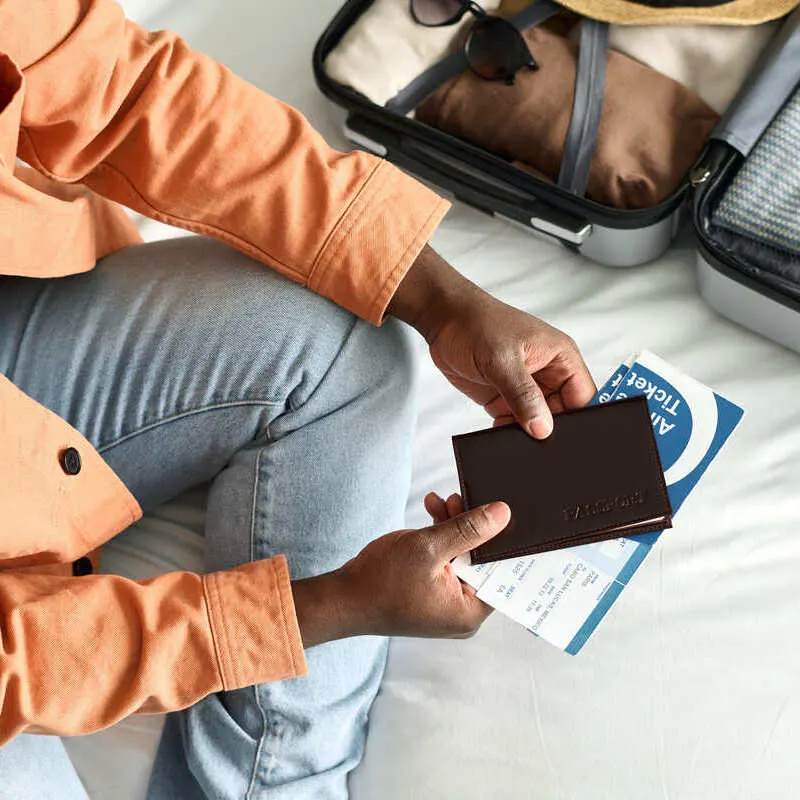 Young Male Traveler Packing His Bags Ahead Of An International Trip As He Holds Up A Passport.jpg