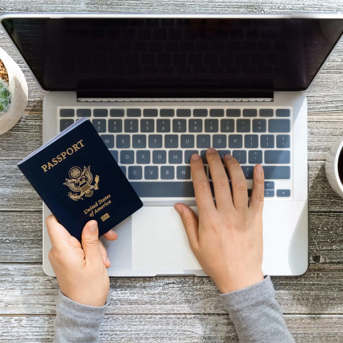 American Traveler Using Their Computer As They Hold An U.S. Passport