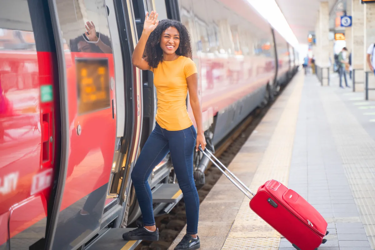 Smiling woman with luggage boarding train