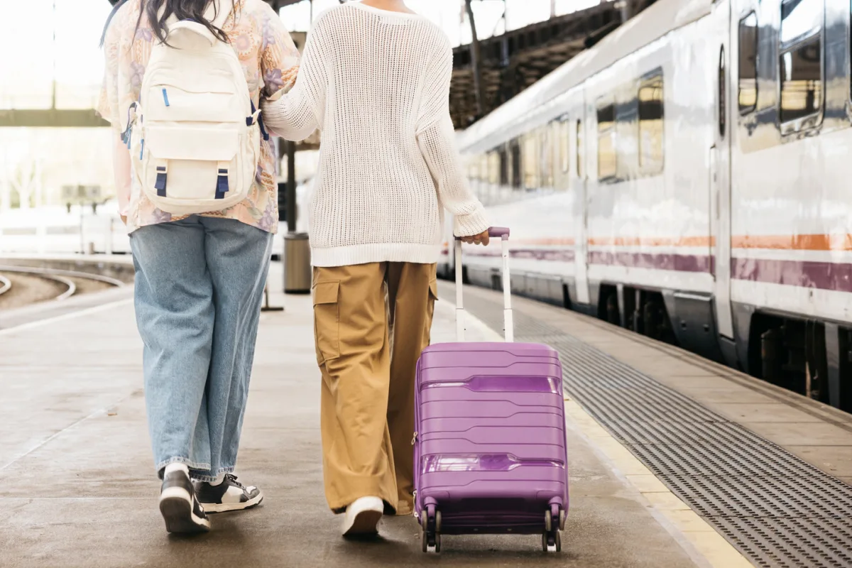 2 women with luggage walking toward train