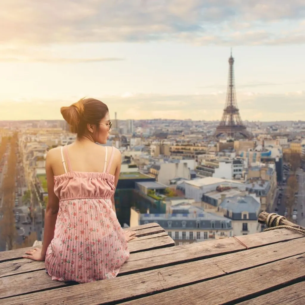 Young Woman Sat On A Rooftop Overlooking Paris, France