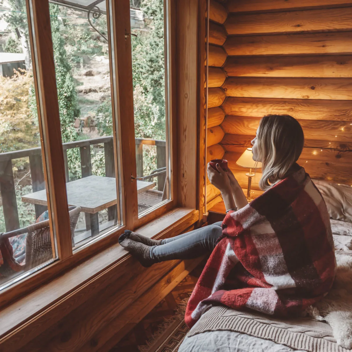 Woman with hot beverage in cozy cabin