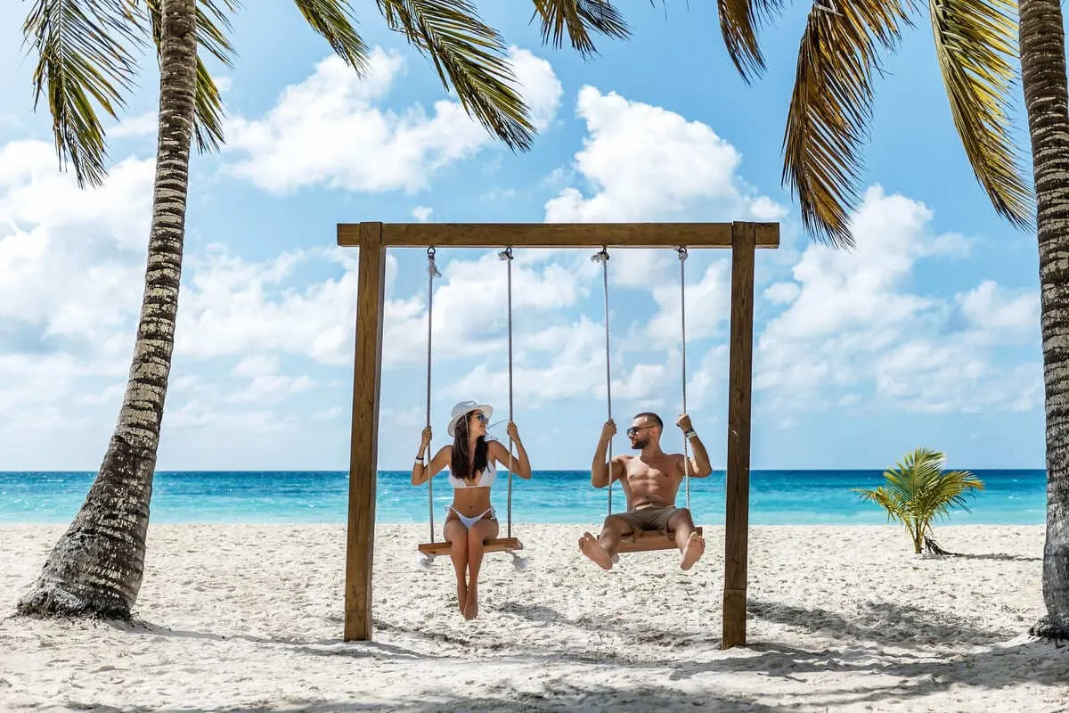 Couple Sitting On A Swing On A Beach In Punta Cana, Dominican Republic