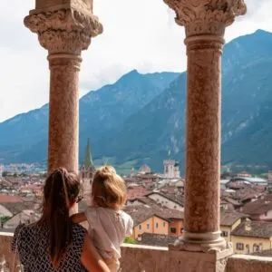 Young Woman With Her Child Admiring A View Of Trento, Italy