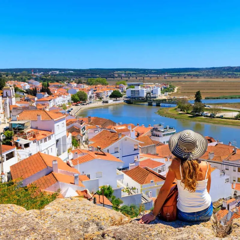 A Young Woman Admiring A View Of Alcacer Do Sal, Portugal