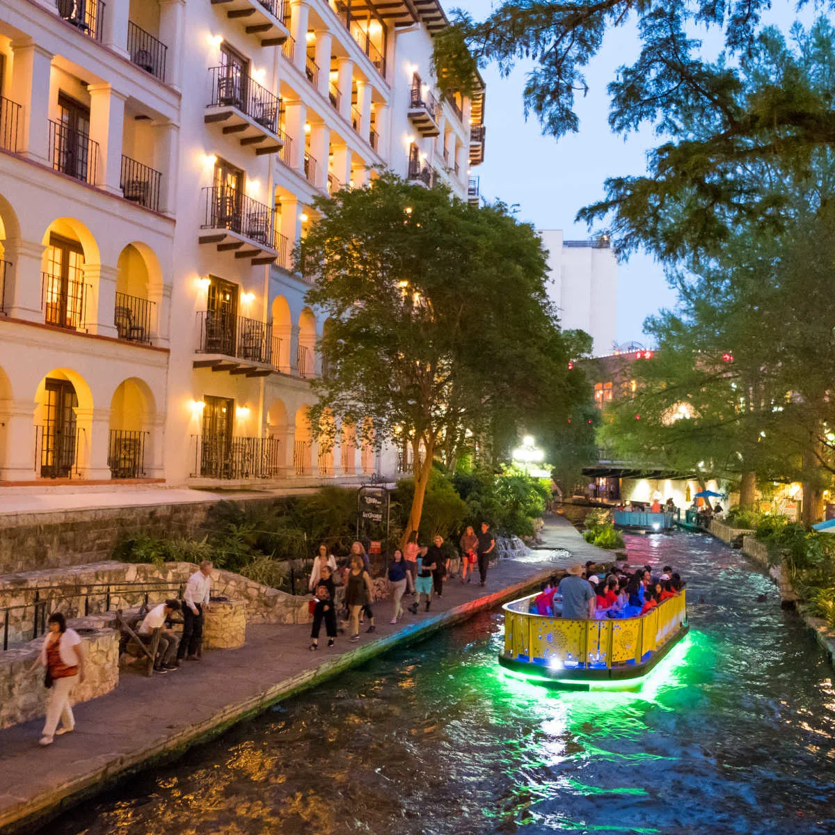 Boat ride through San Antonio River Walk in evening