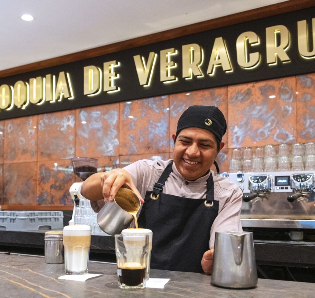 Restaurant barista in Mexico happy serving tourist a coffee