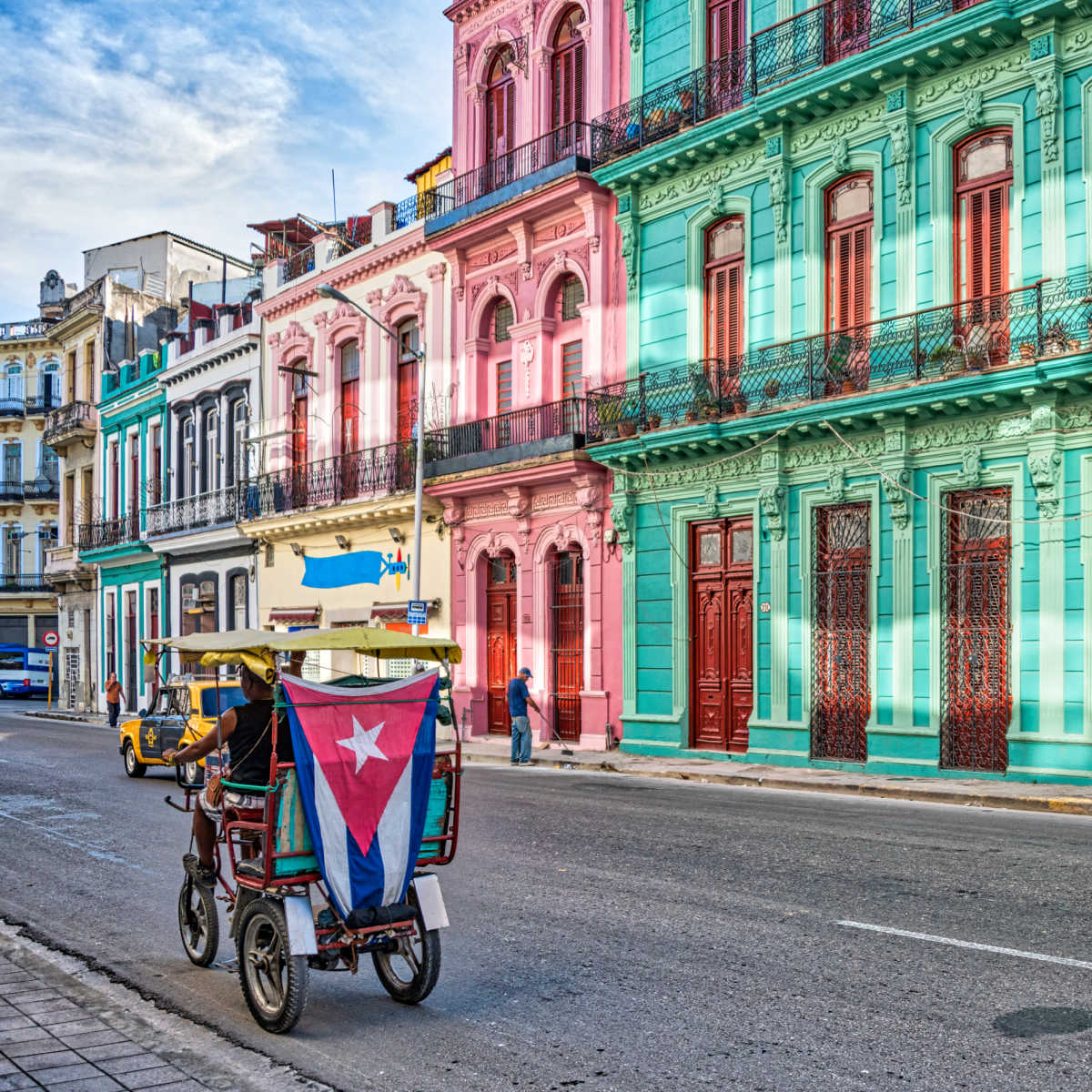 Tricycle passing colorful row of historic buildings in Havana, Cuba