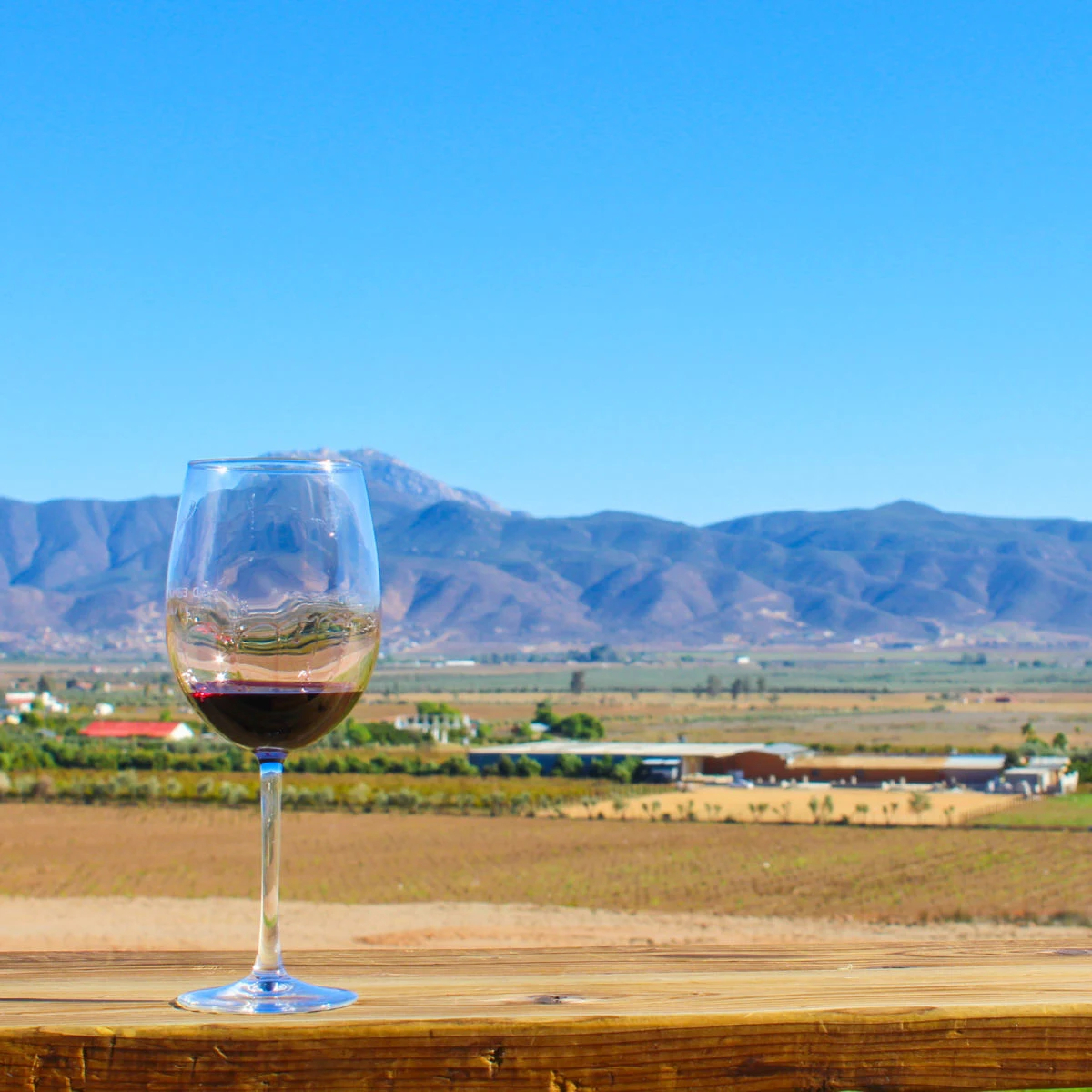 Wine glass on ledge backdropped by mountains in Valle de Guadalupe, Mexico