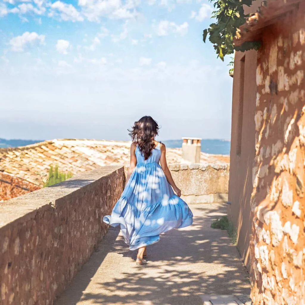 Young Woman Walking Down A Cobbled Street In Provence, France