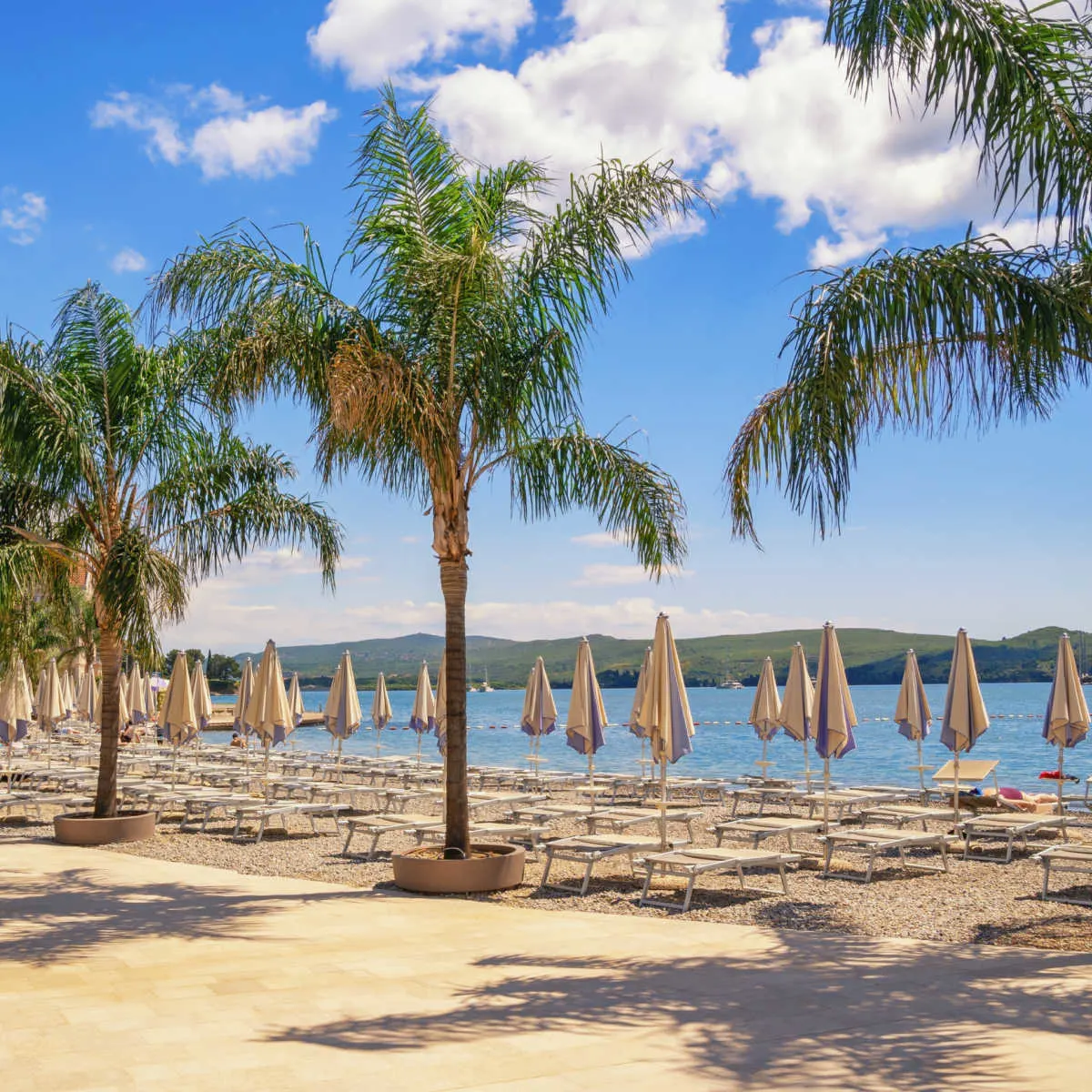 Beach in Tivat, Montenegro with chaise lounges and beach umbrellas