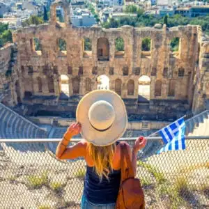 Tourist holding Greek flag at Theatre of Herodion - Athens, Greece