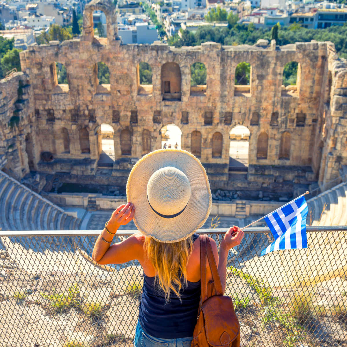 Tourist holding Greek flag at Theatre of Herodion - Athens, Greece