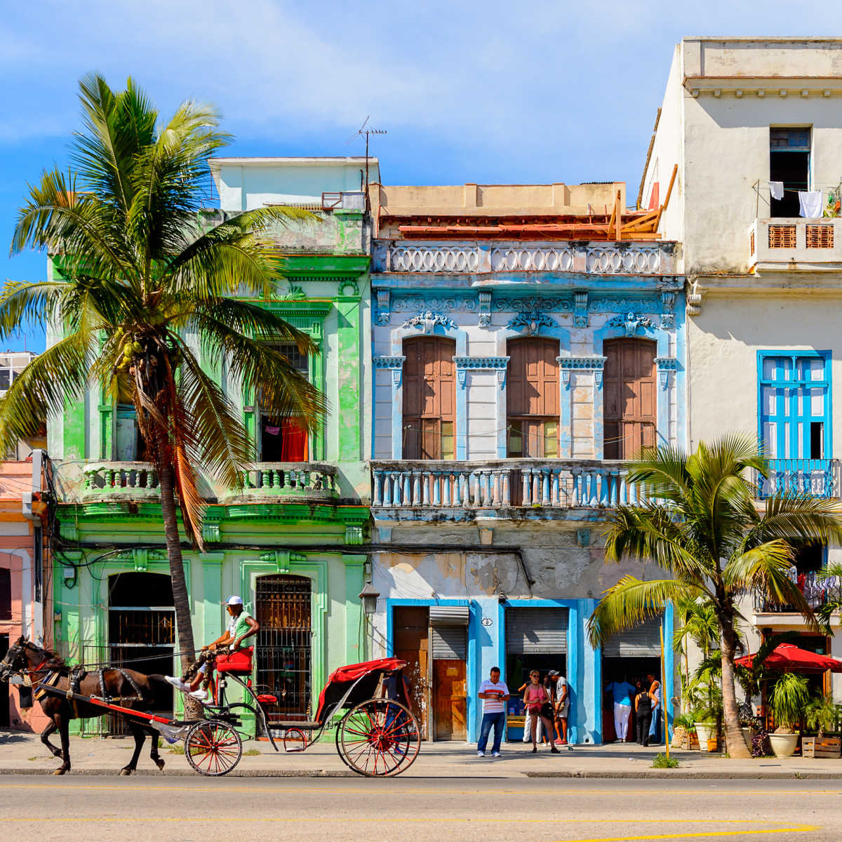 Horse carriage passing pastel buildings in Havana