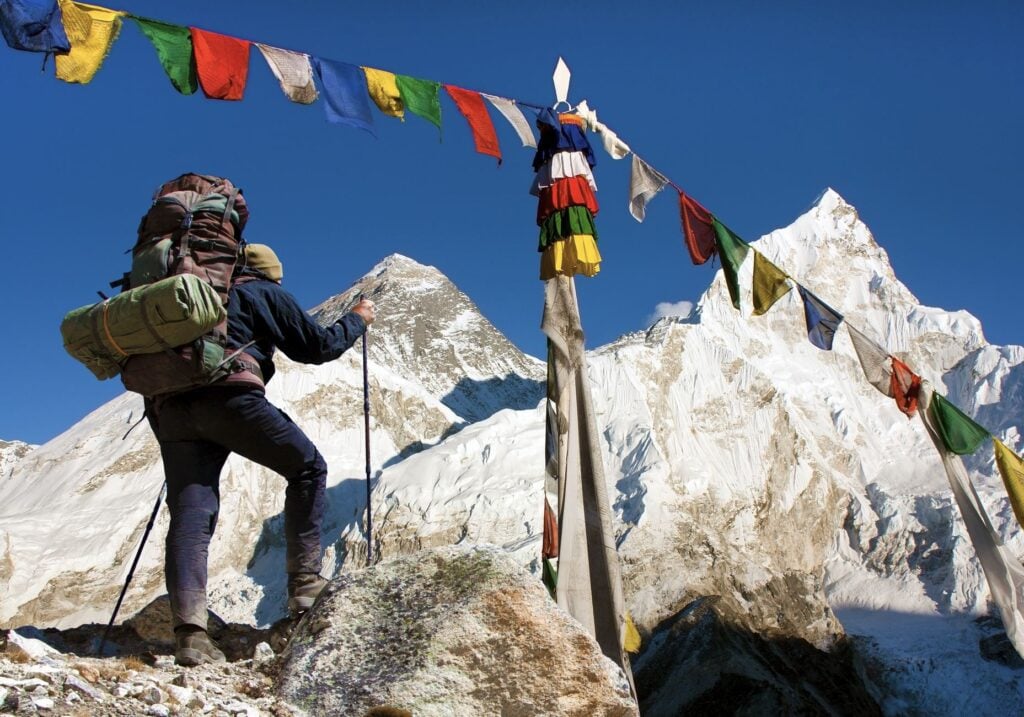 View of Everest with hiker or tourist and buddhist prayer flags