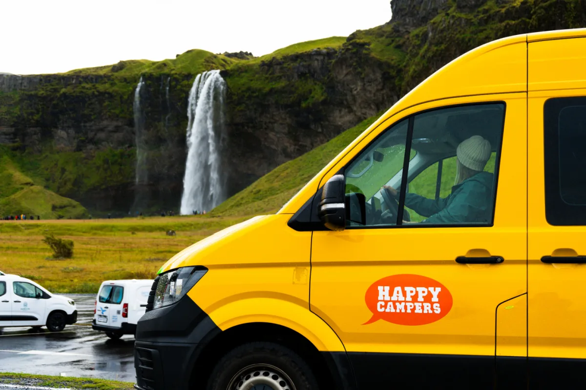 Woman in Camper Van in Iceland in front of Seljalandsfoss Waterfall.