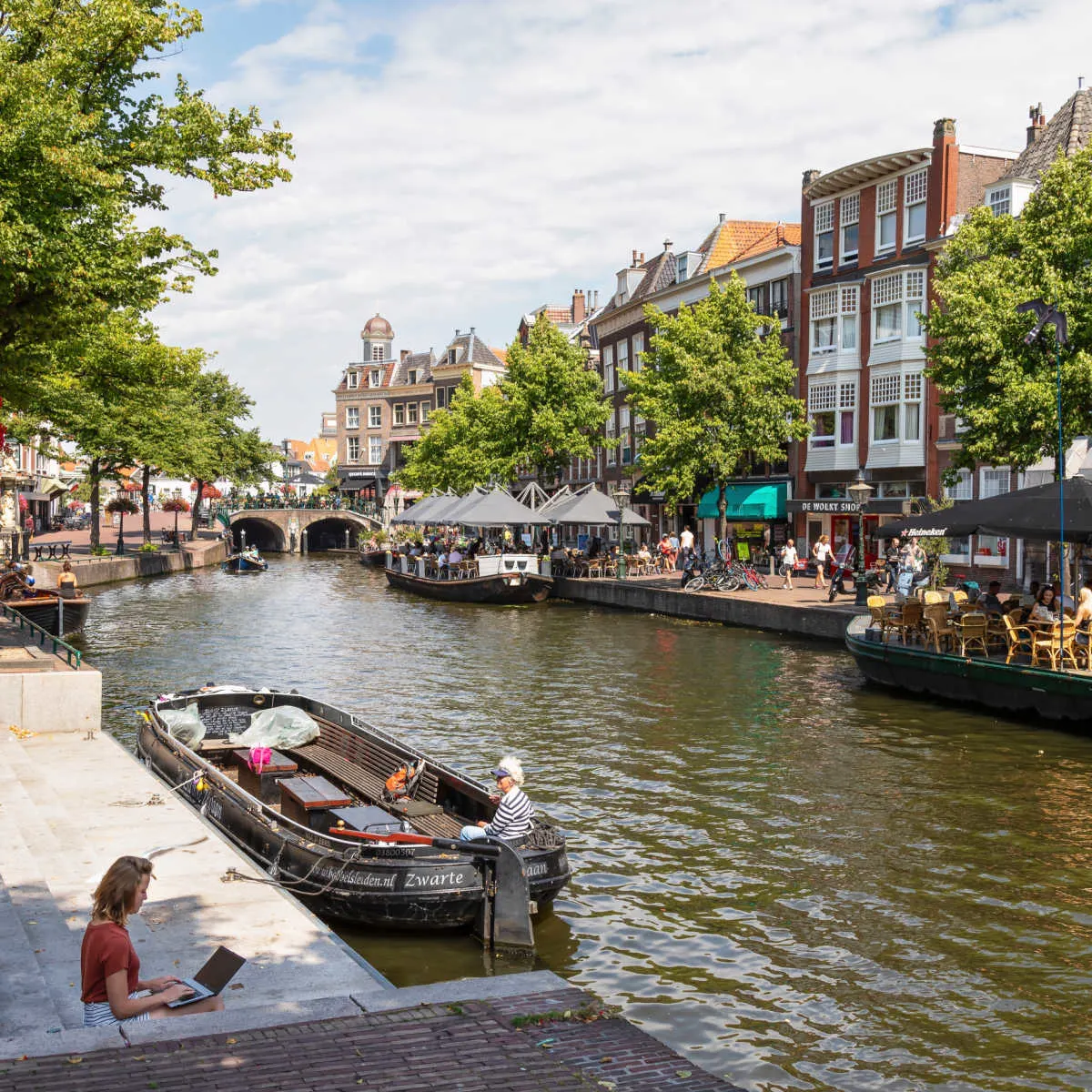 Woman on laptop near canal in Netherlands