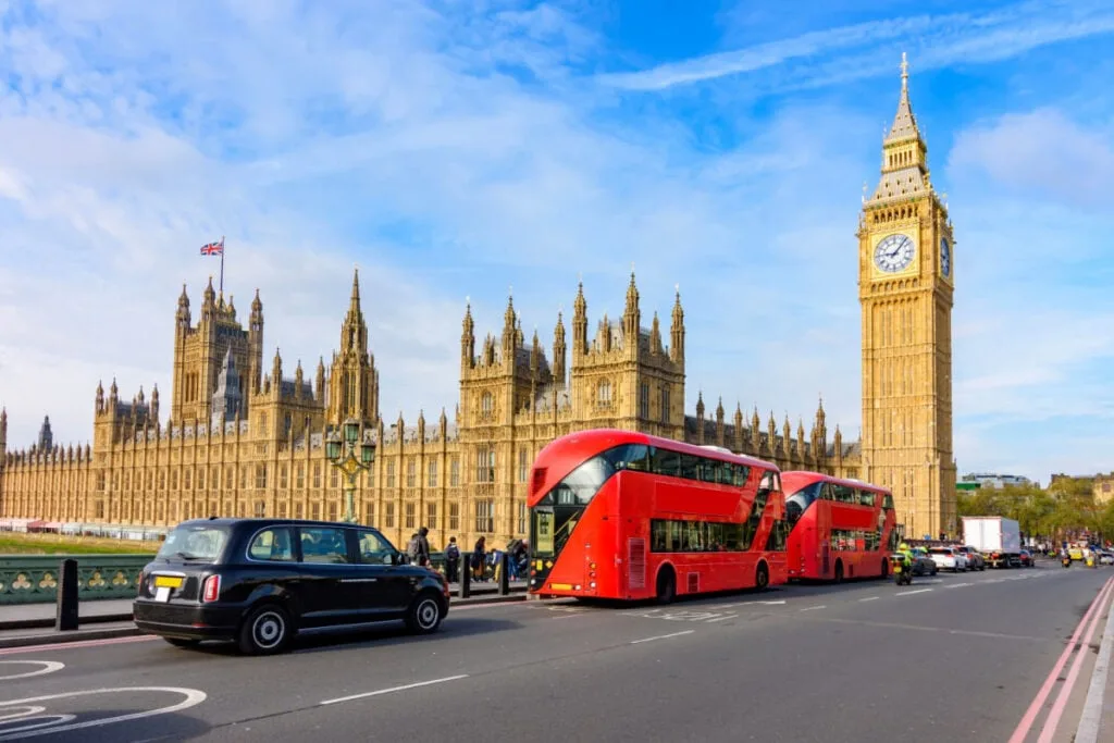 Double-decker buses and black cab on Westminster bridge with Big Ben and Houses of Parliament at background, London, UK