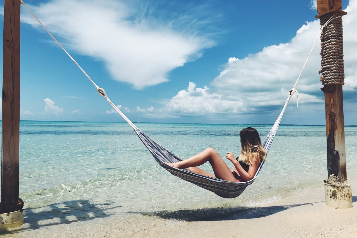 Tourist relaxing on beach hammcok in Eleuthera, Bahamas