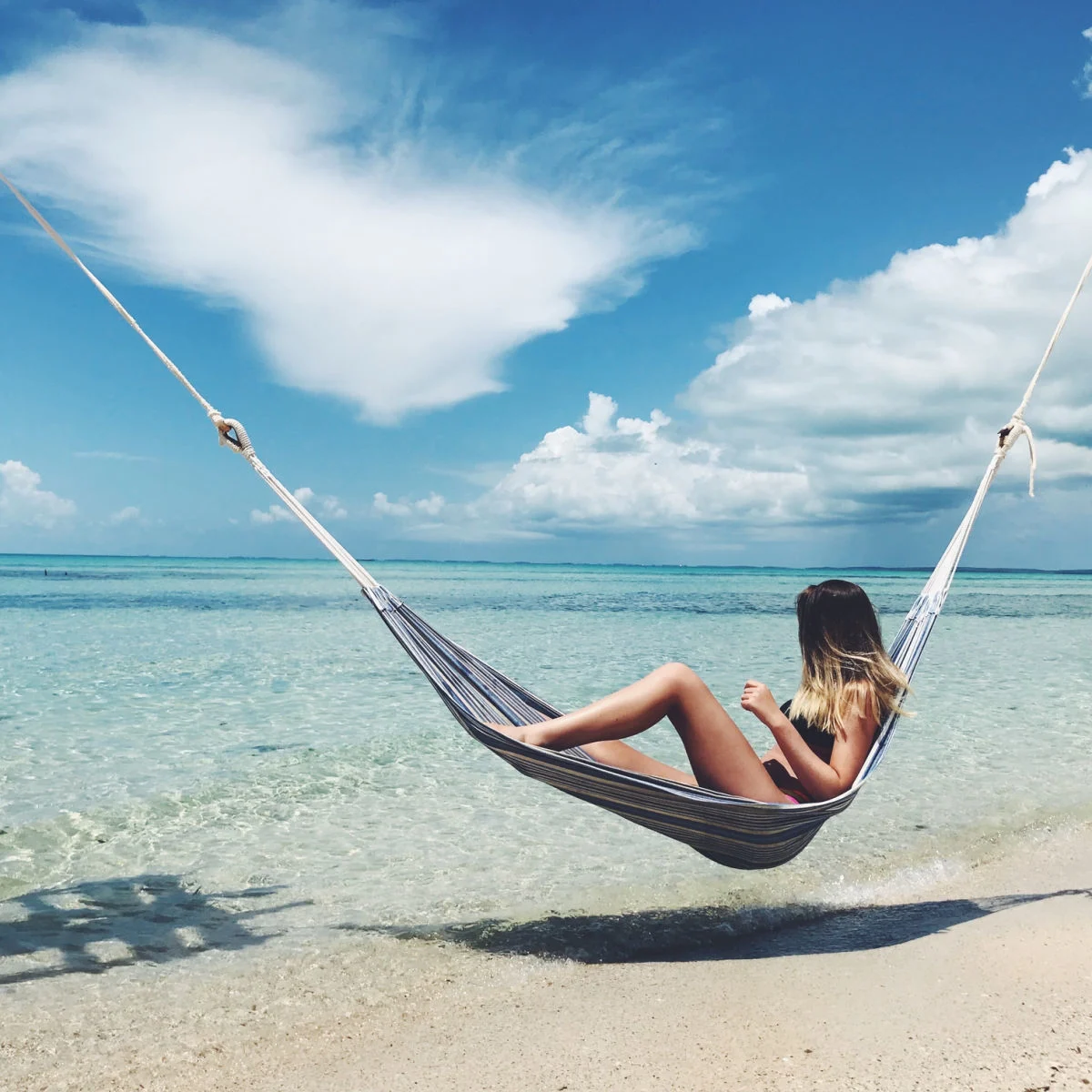 Tourist relaxing on beach hammcok in Eleuthera, Bahamas