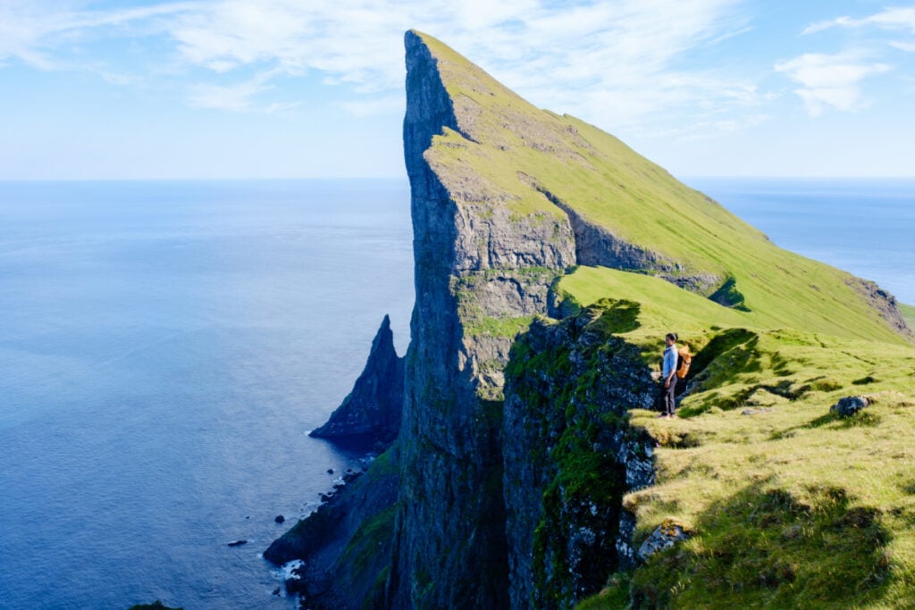 Adventure seekers stand atop stunning Mylingur cliffs in the Faroe Islands, capturing the majestic beauty of the rugged landscape.