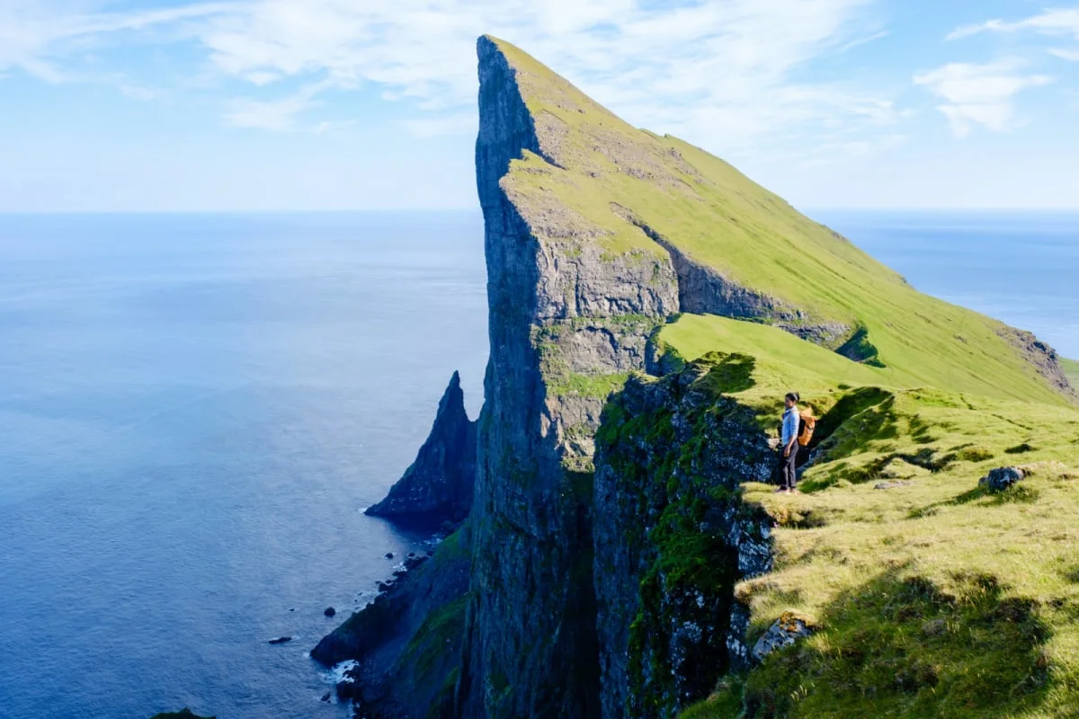 Europe’s Most Untouched Islands Are Now Easier To Reach Than Ever Adventure seekers stand atop stunning Mylingur cliffs in the Faroe Islands, capturing the majestic beauty of the rugged landscape.