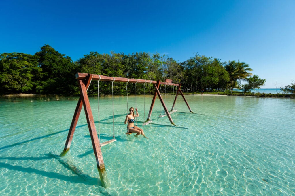 美丽的女游客在墨西哥巴卡拉尔湖皮划艇之旅中在秋千上放松。