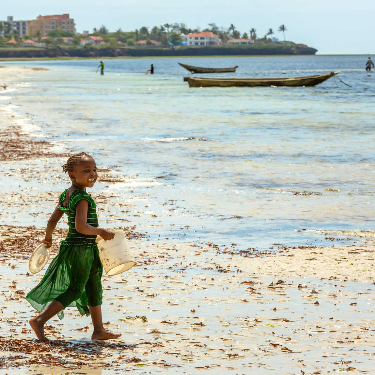 Child carrying bucket on Mombasa, Kenya beach