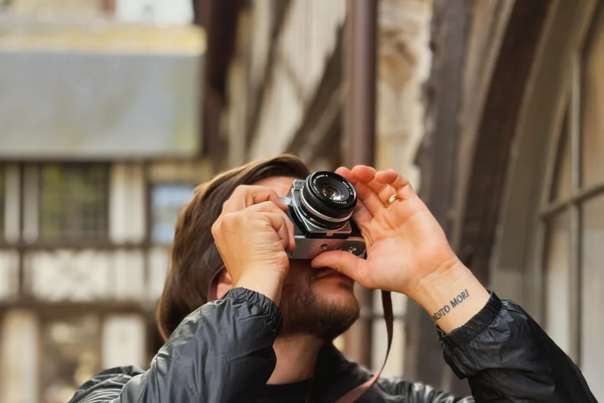 Man taking photo with film camera of building in Rouen, France