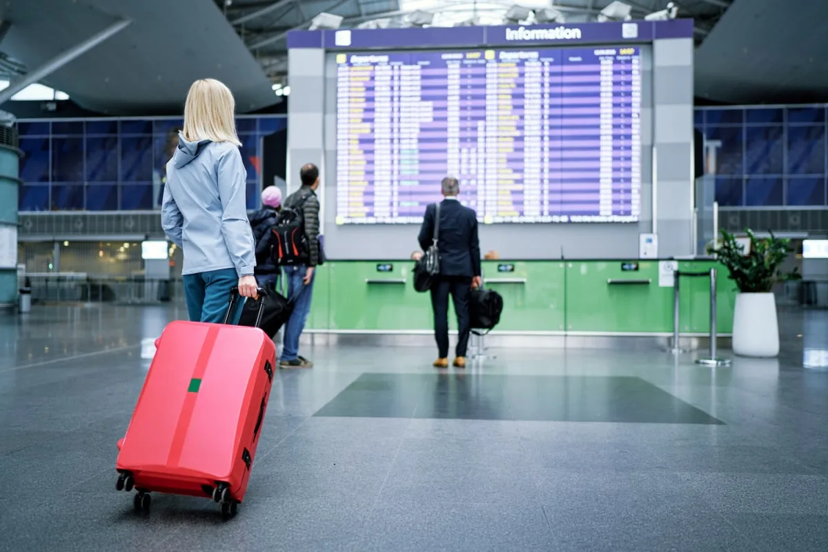 Female traveler with luggage viewing departure board