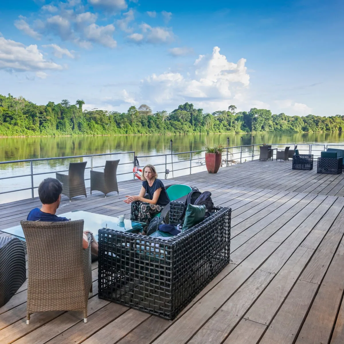 Tourists sitting on a deck overlooking the Suriname river