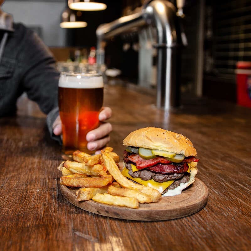 A Male Tourist Enjoying A Beer And Burger In Cordoba, Argentina