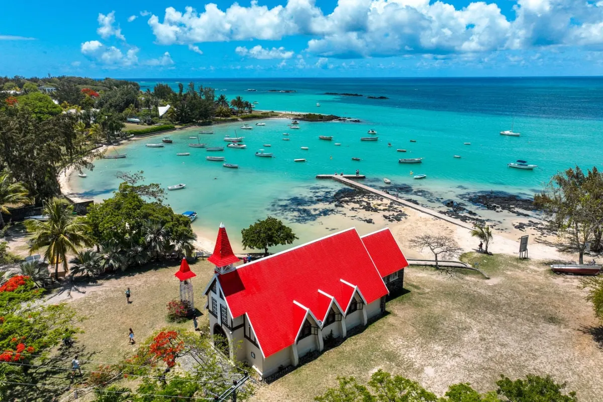 Aerial view of Notre-Dame Auxiliatrice with red rooftop and lagoon in Cap Malheureux village in Mauritius