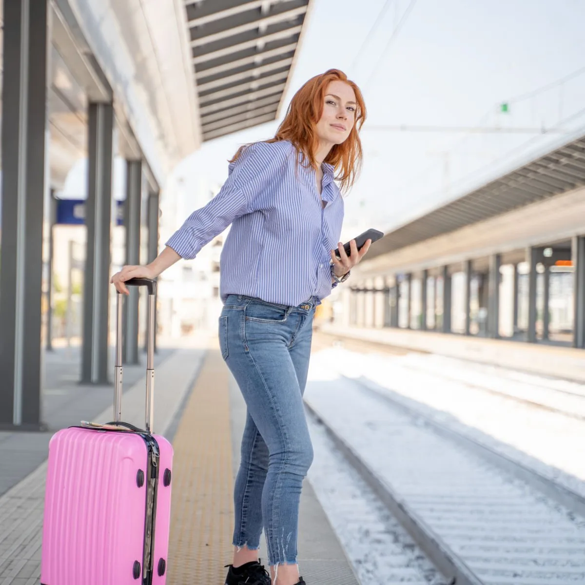 Woman with pink luggage waiting for train