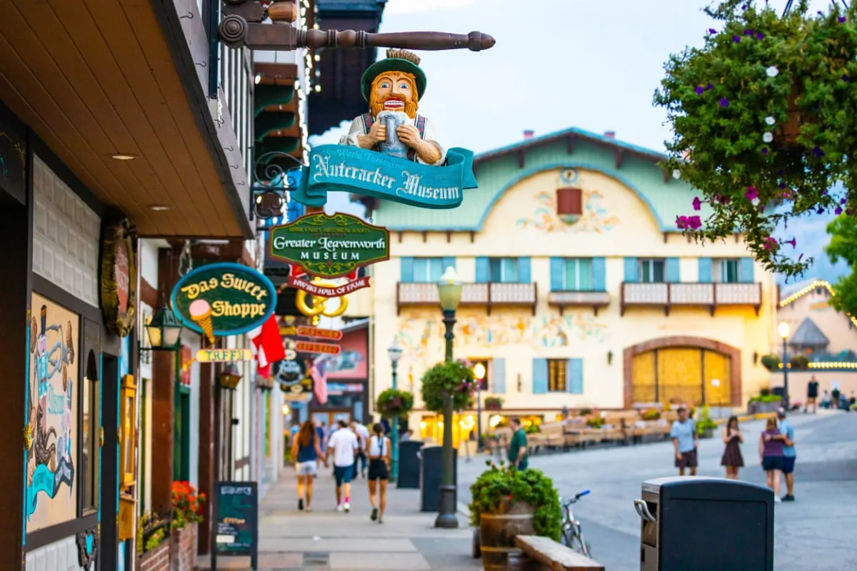 People enjoy a warm summer evening on the street in Leavenworth city center among Bavarian-style buildings and businesses