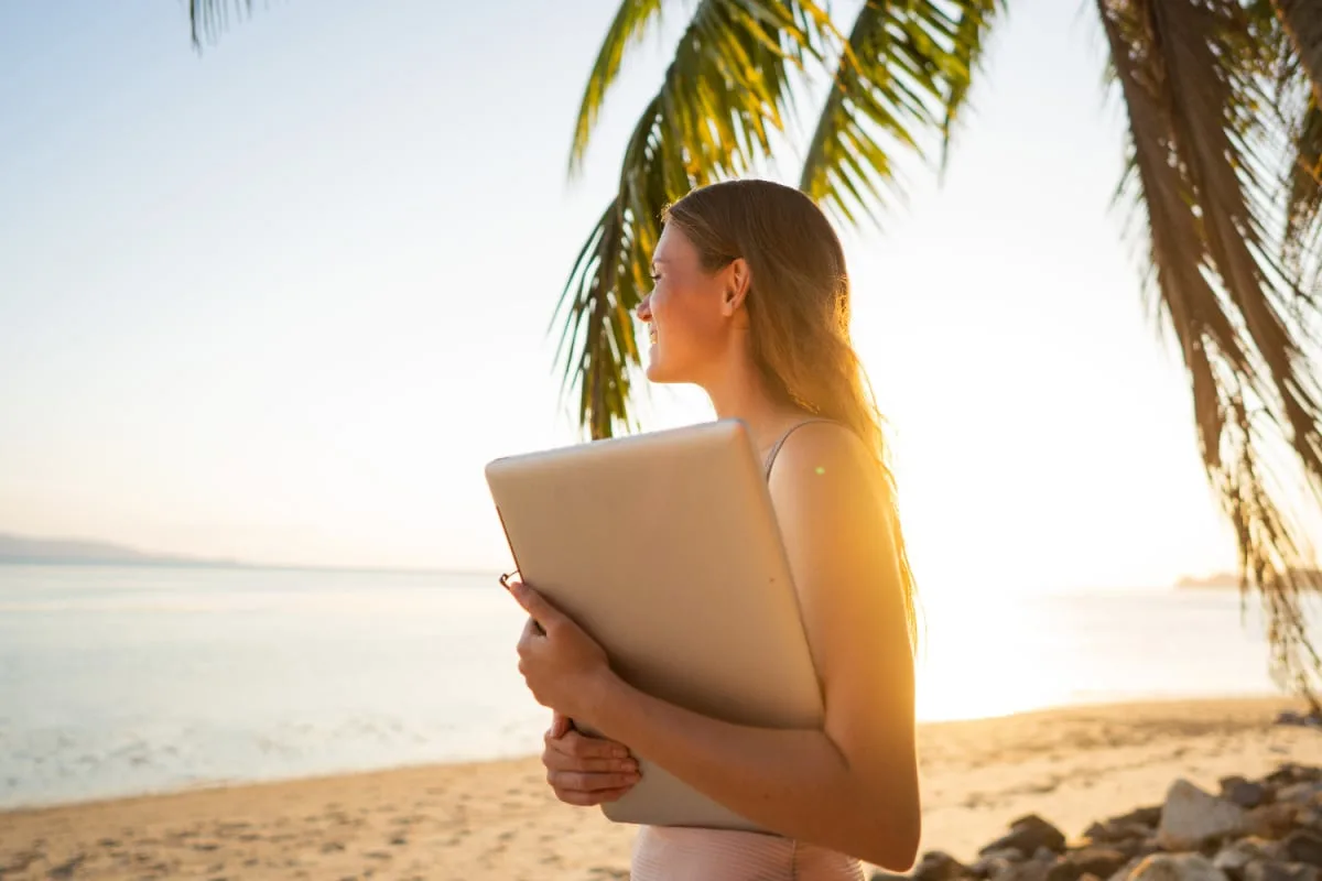 Woman holding laptop on tropical beach