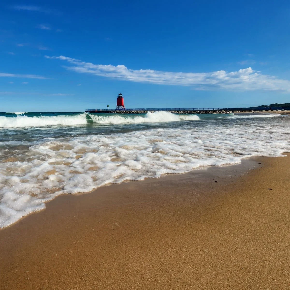 Waves hitting the beach with the Charlevoix South Pier Lighthouse