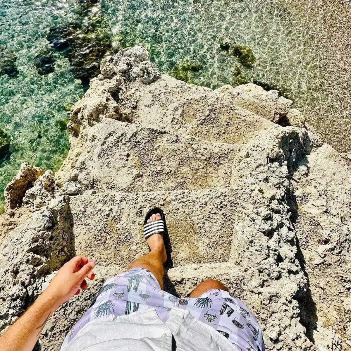 A Tourist Going Down Stone Steps Leading Down To The Mediterranean Sea In Anthony Quinn Bay, Rhodes, Greece