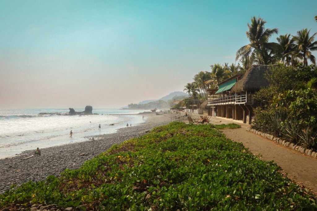 Beautiful beachside view of El Tunco in El Salvador with surfers and palm trees during a sunny day