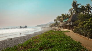 Beautiful beachside view of El Tunco in El Salvador with surfers and palm trees during a sunny day