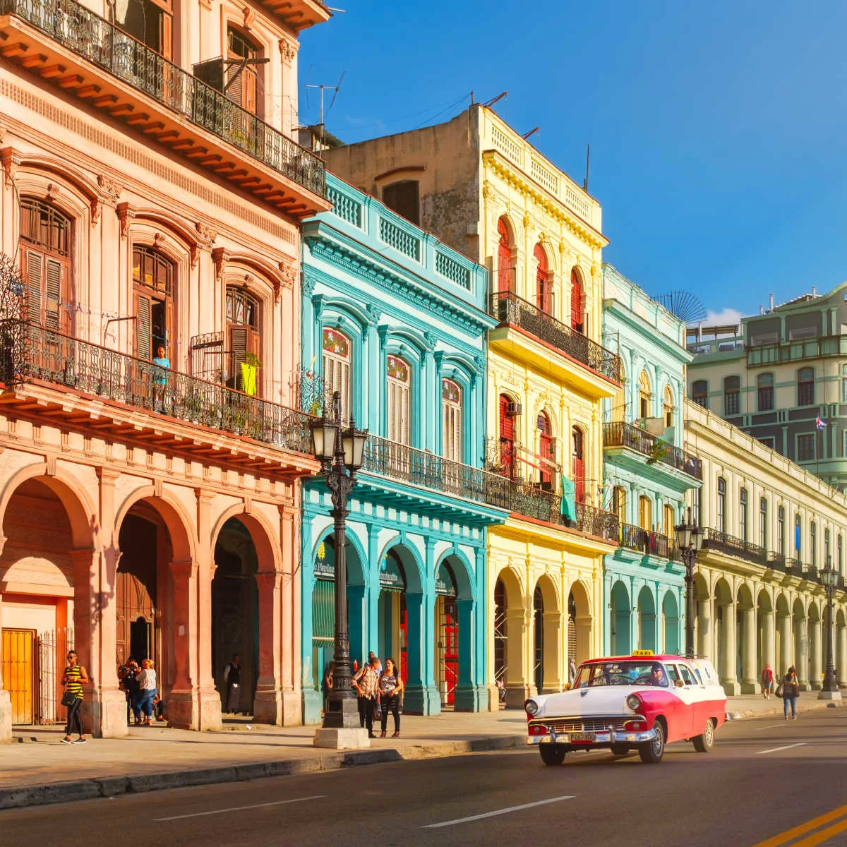 Classic car passing Havana's pastel buildings