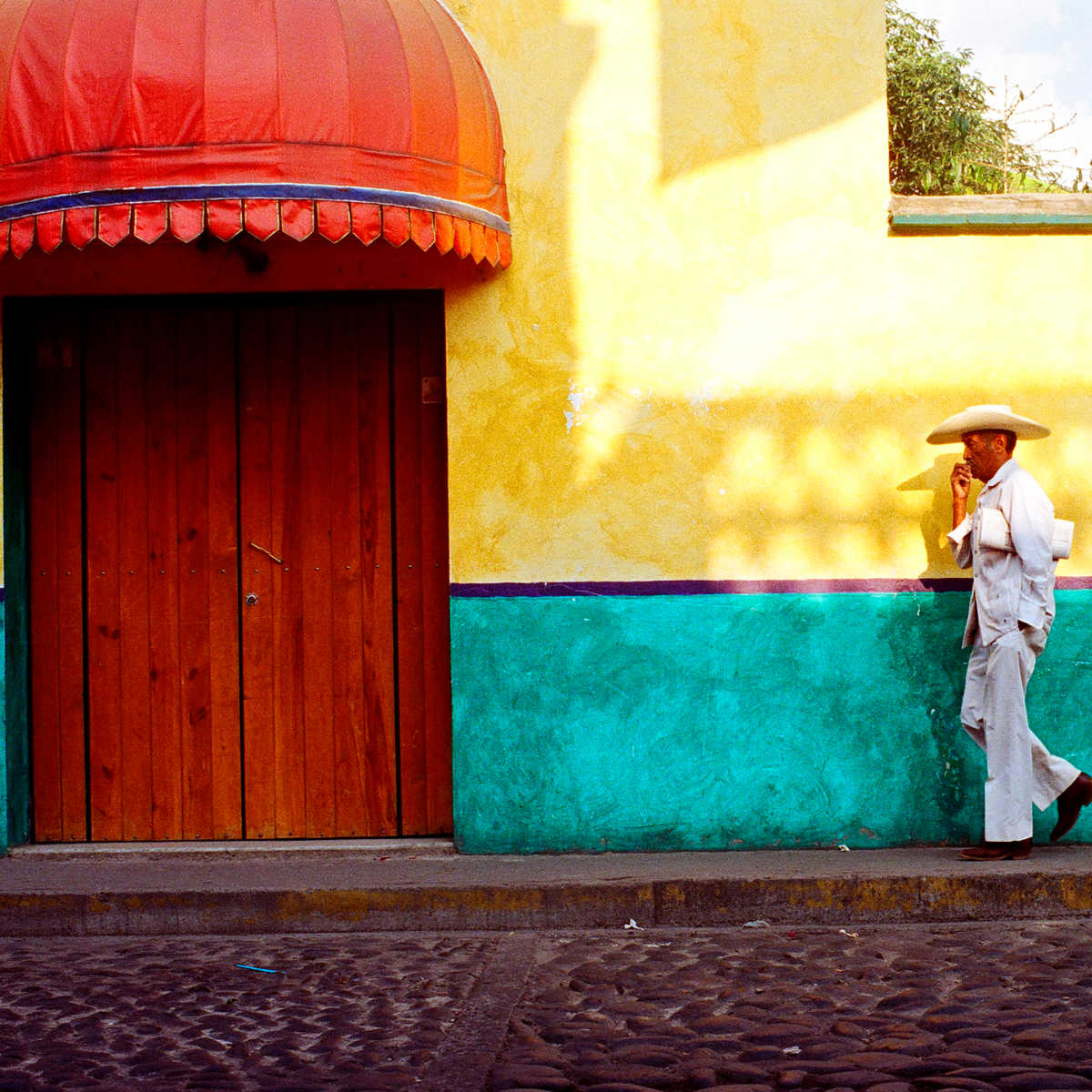 Man in traditional clothing wlaking past historic building in Tepoztlan