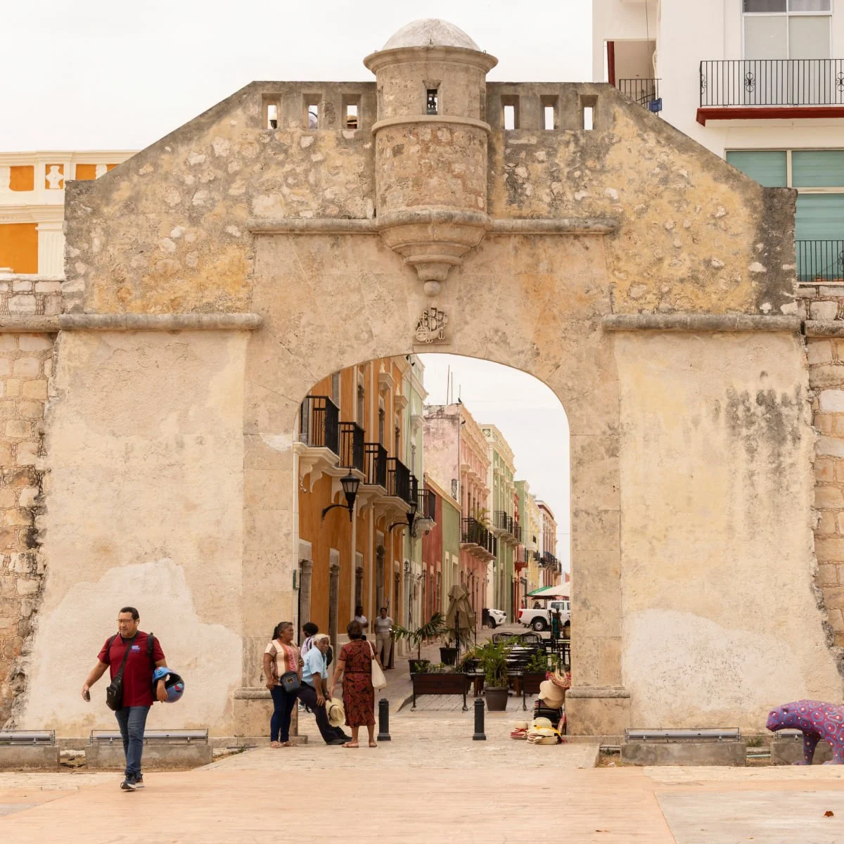 People walk through the historic gate of the colonial walls of Campeche