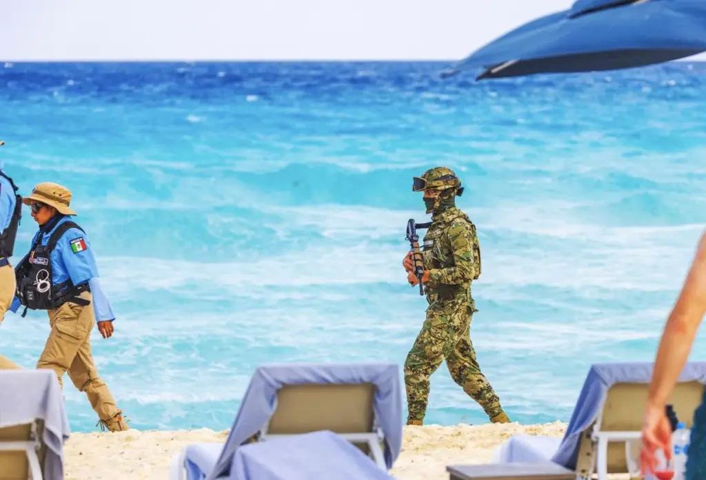 সৈন্য এবং ইউনিফর্মধারী পুলিশ অফিসাররা ক্যানকুন সমুদ্র সৈকতে হাঁটছেন