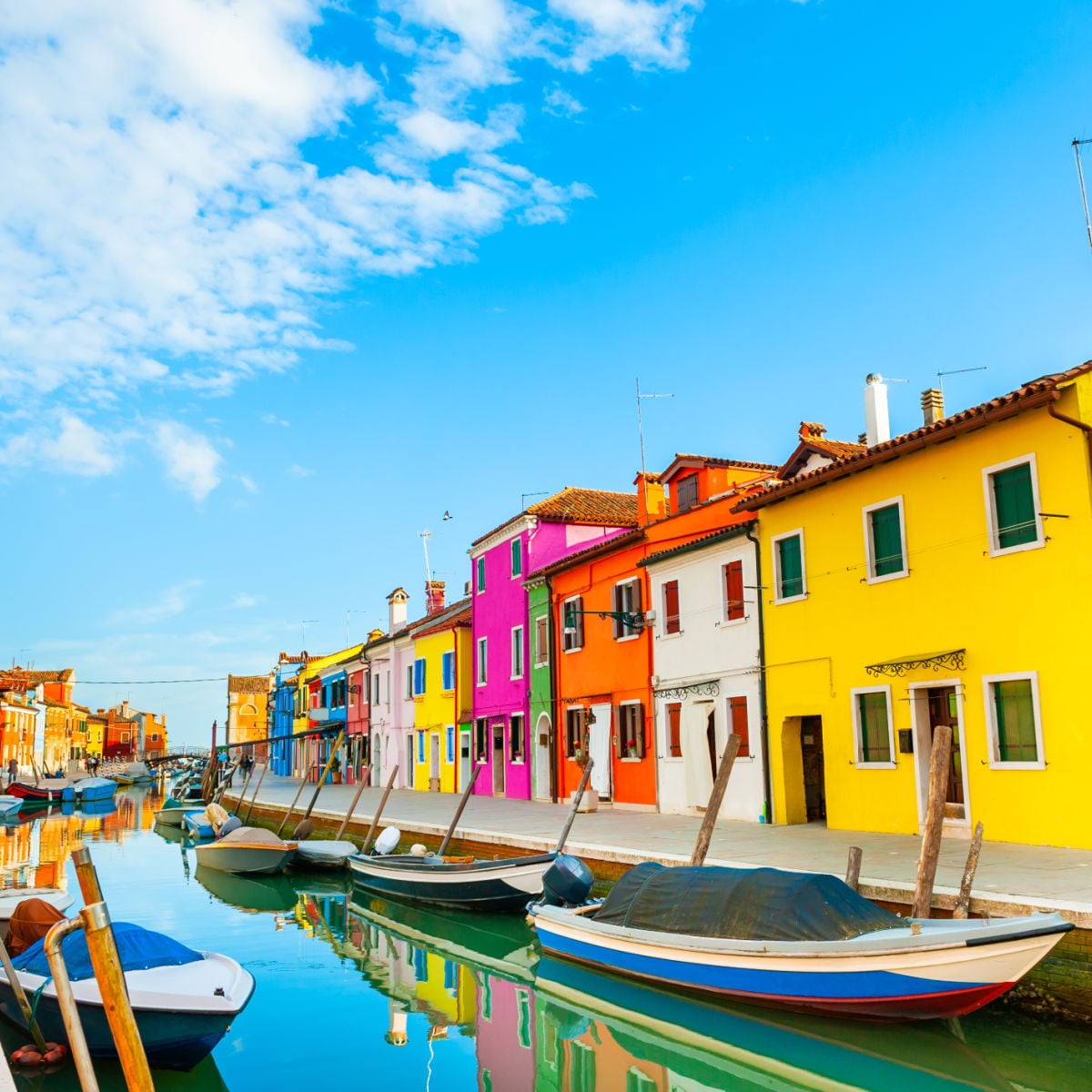 Colorful row of homes and boats along Burano, Italy canal